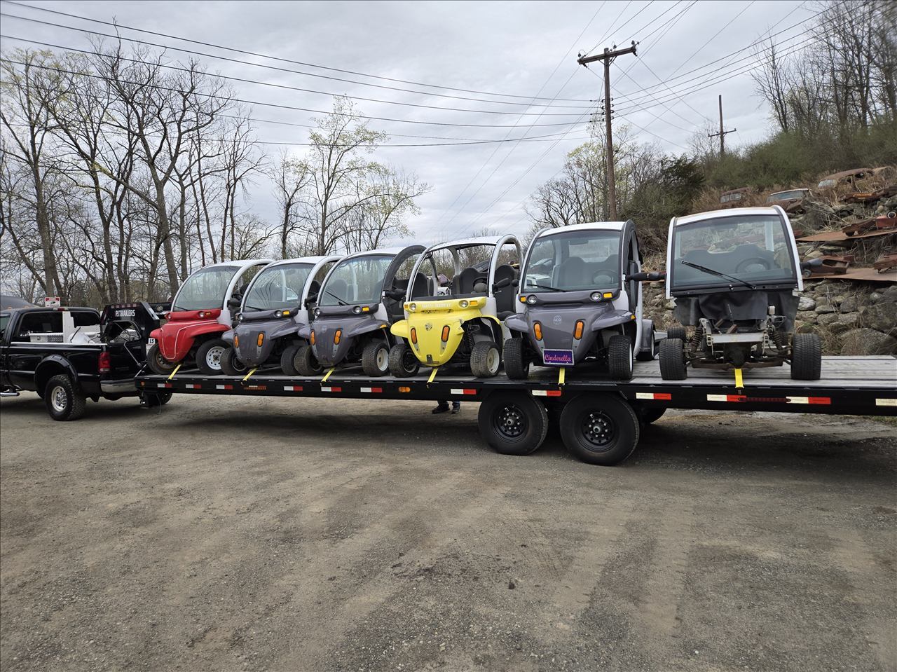 Black truck pulling a flatbed trailer loaded with GEM carts